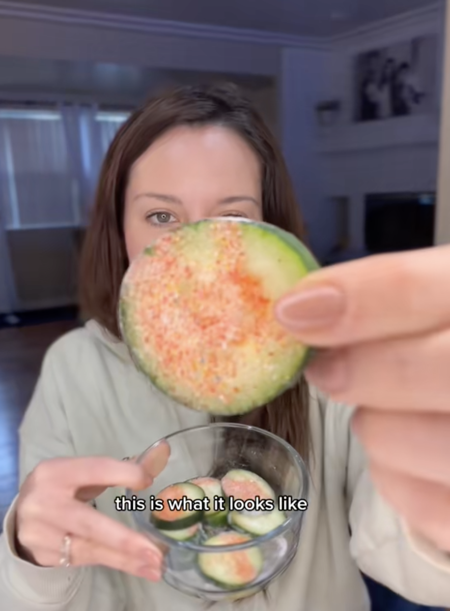 Close-up of a woman holding a piece of cucumber with seasoning. Text reads: &quot;this is what it looks like.&quot;